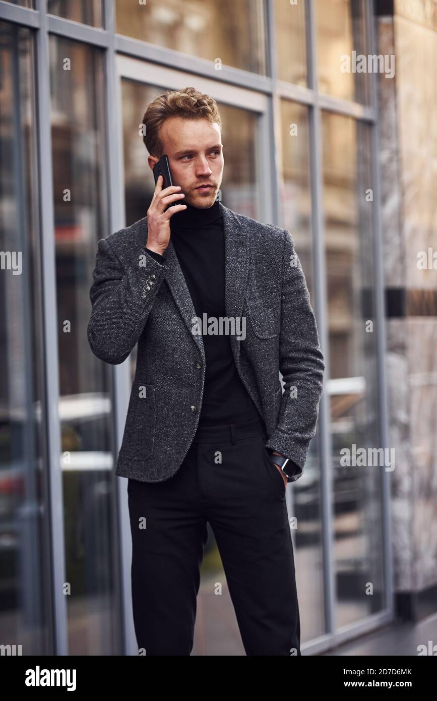 Homme en tenue élégante et habillée dehors contre le bâtiment moderne  parlant par téléphone Photo Stock - Alamy