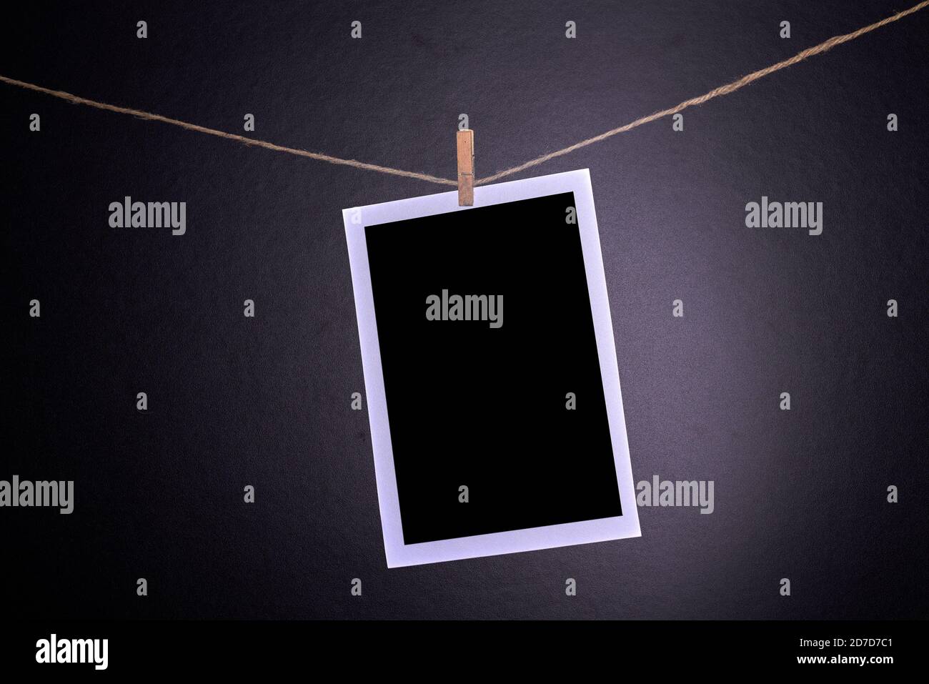 Gros plan de photographies polarioïdes vierges accrochées à une corde à linge dans une chambre noire. Banque D'Images