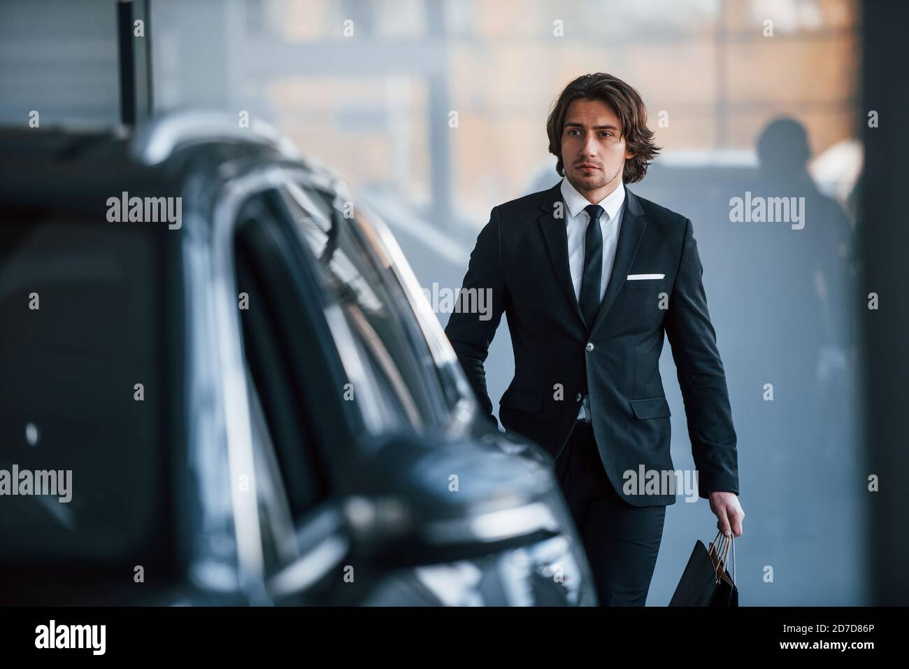 Portrait du beau jeune homme d'affaires en costume noir et cravate et avec  un sac à provisions près de la voiture moderne Photo Stock - Alamy