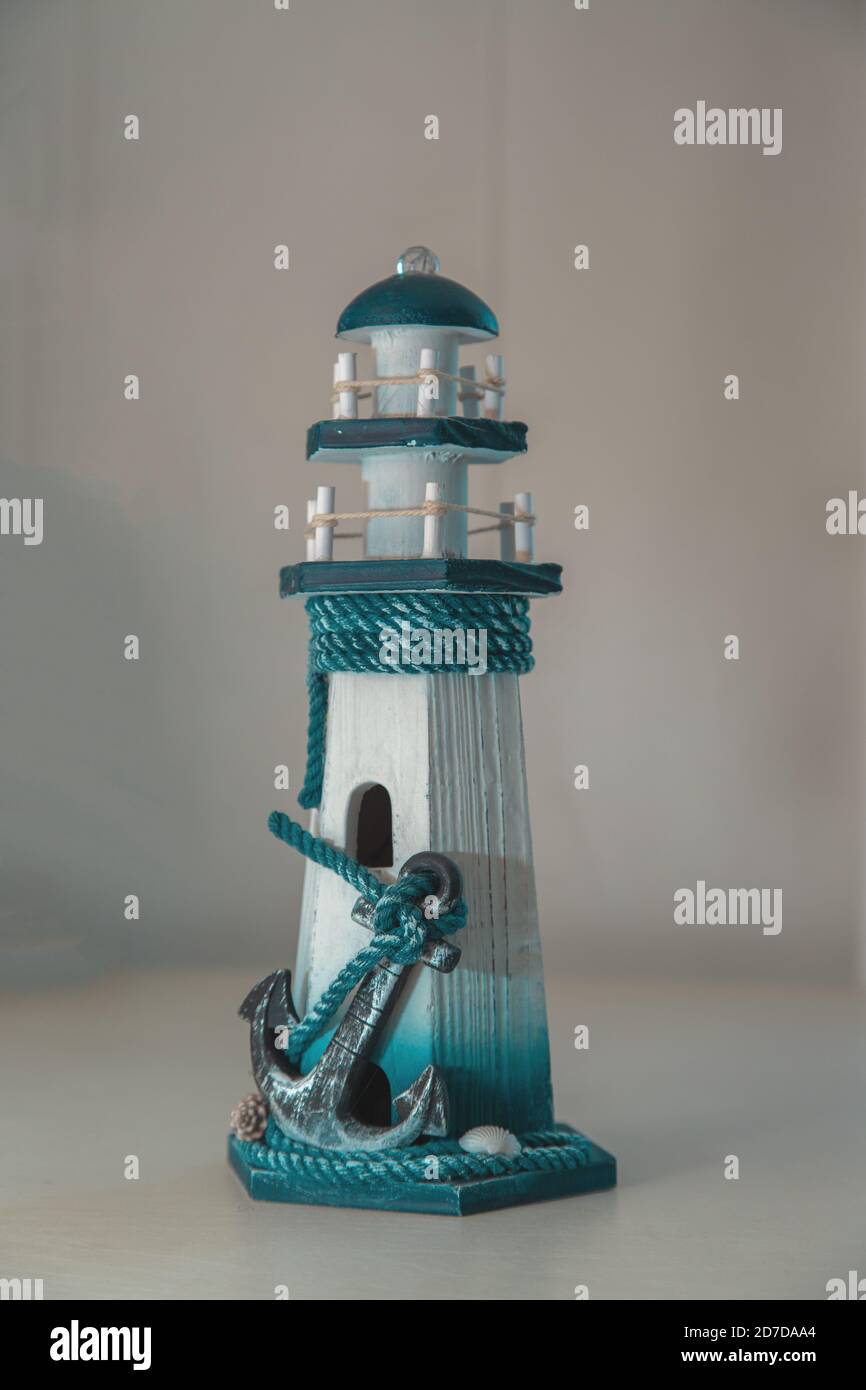 Une figurine sous la forme d'un phare avec une grande ancre au premier plan. Arrière-plan flou. Banque D'Images