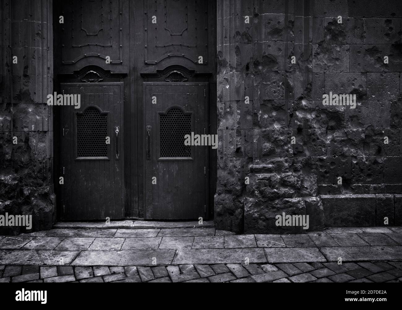 Image noir et blanc édition sombre.impact de shrapnel contre un mur Et l'ancienne porte du temple Saint Philip Neri à Barcelone en Espagne Banque D'Images