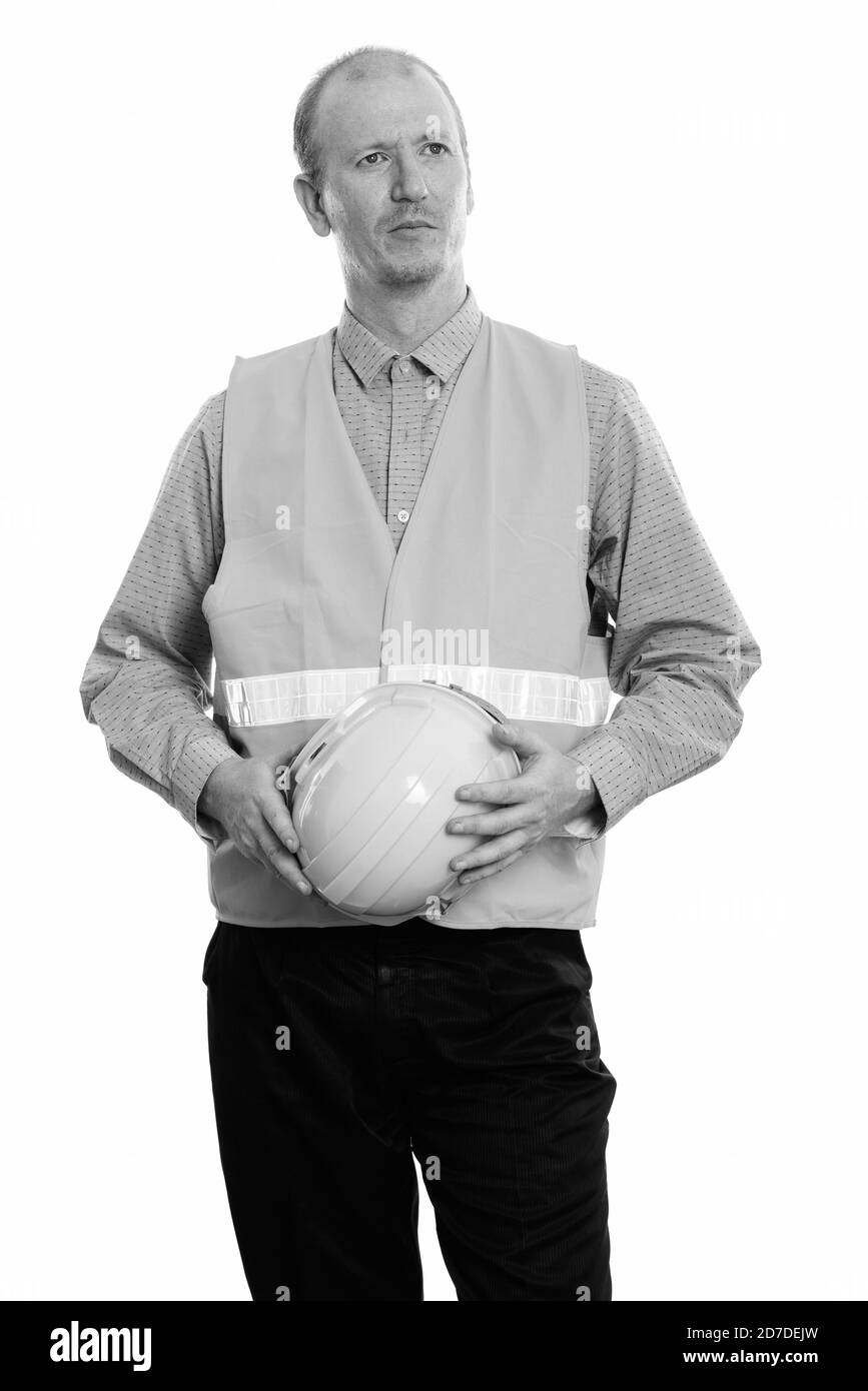 L'homme réfléchi construction worker holding casque de sécurité avec les deux mains Banque D'Images