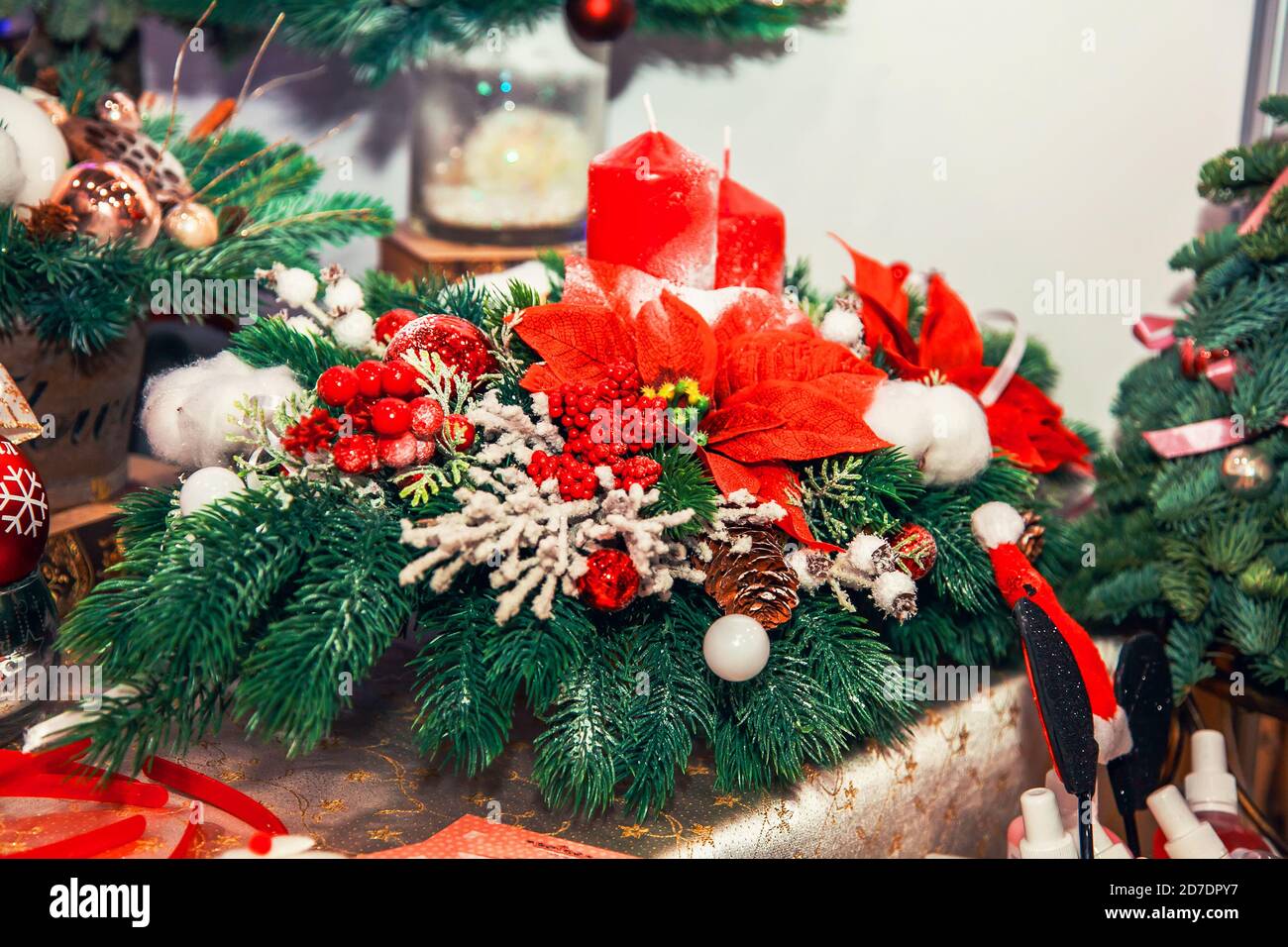 Compositions et décorations de Noël avec bougies en branches de sapin, boules et poinsettia à la foire. Banque D'Images