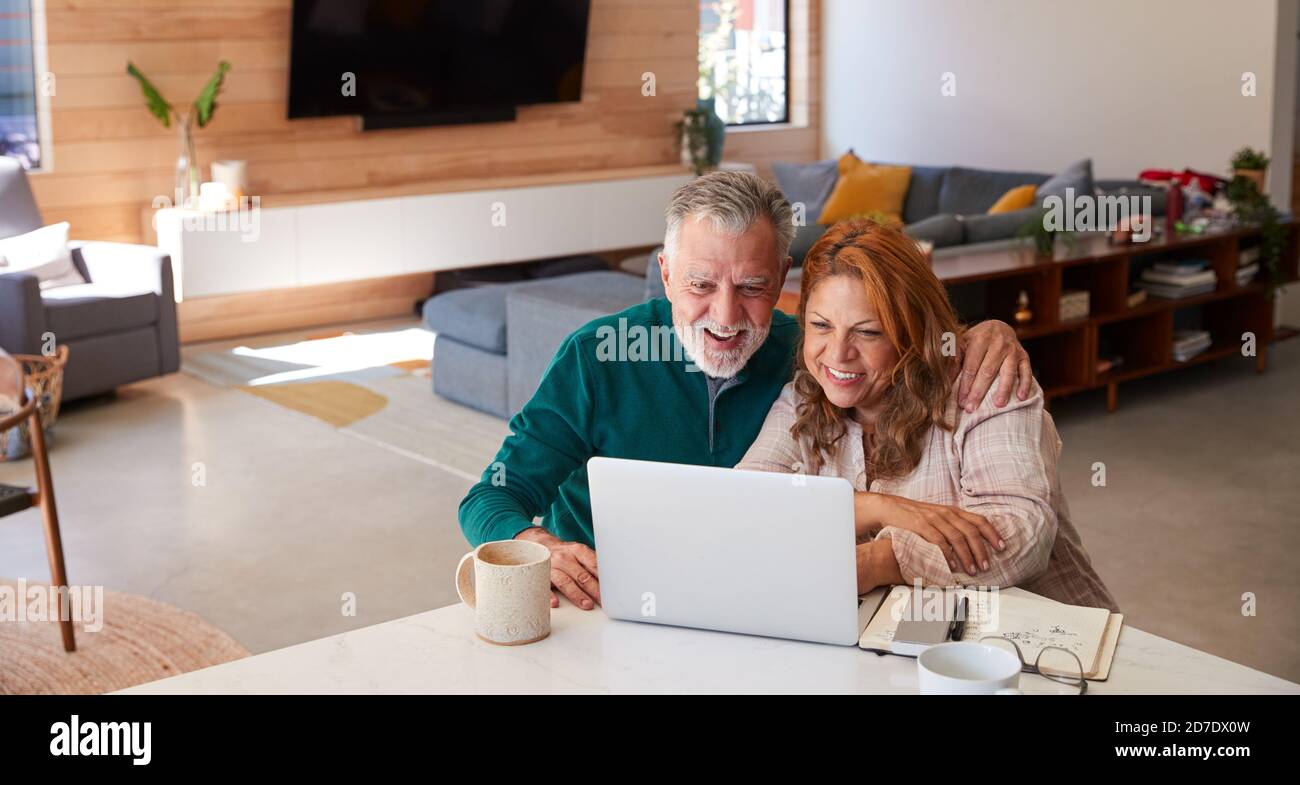 Couple hispanique senior à la maison assis à la table à l'aide d'un ordinateur portable Ensemble Banque D'Images