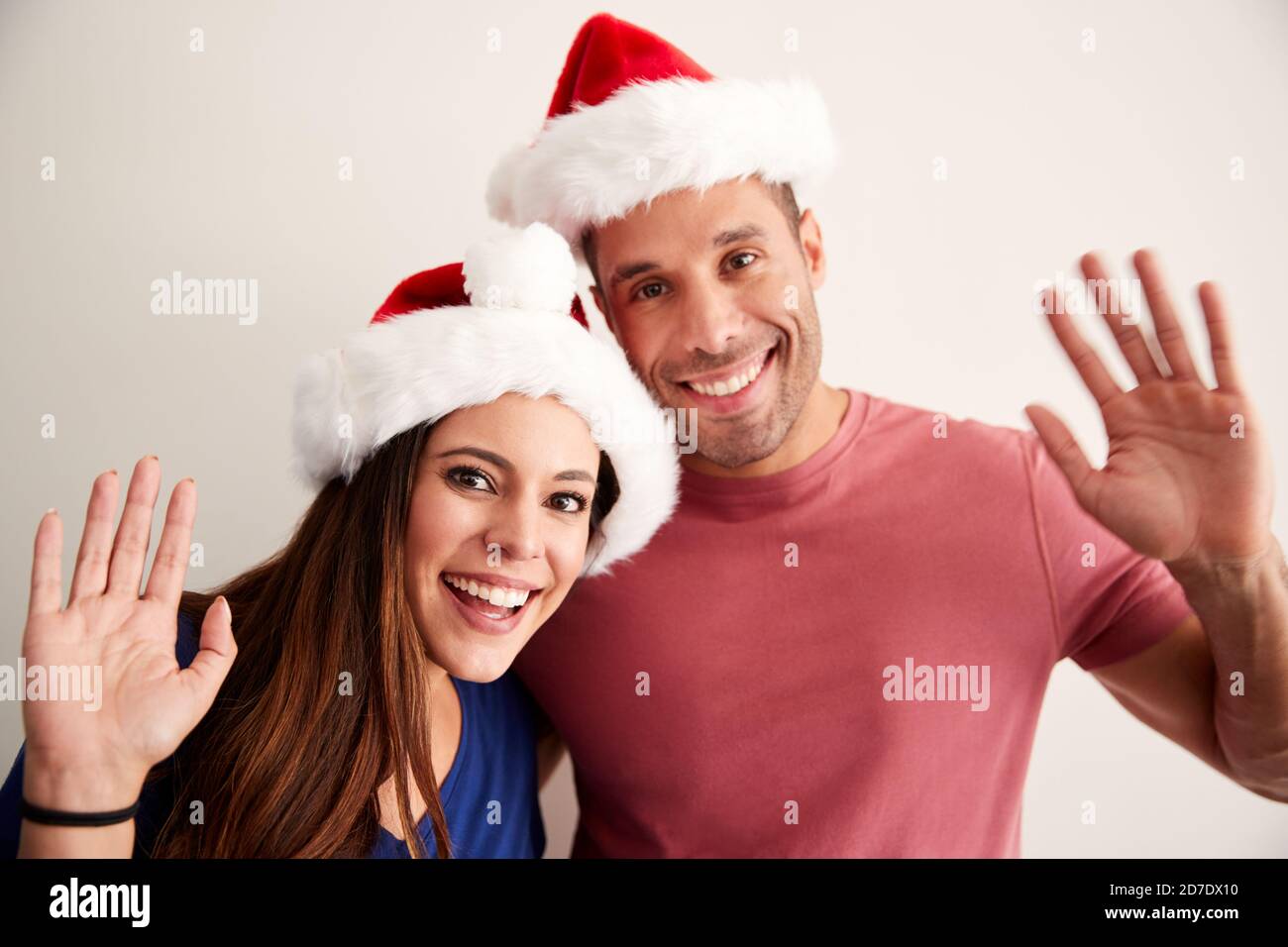 Portrait d'un couple hispanique portant des Santa Hats célébrant les festivités de Noël À la caméra Banque D'Images