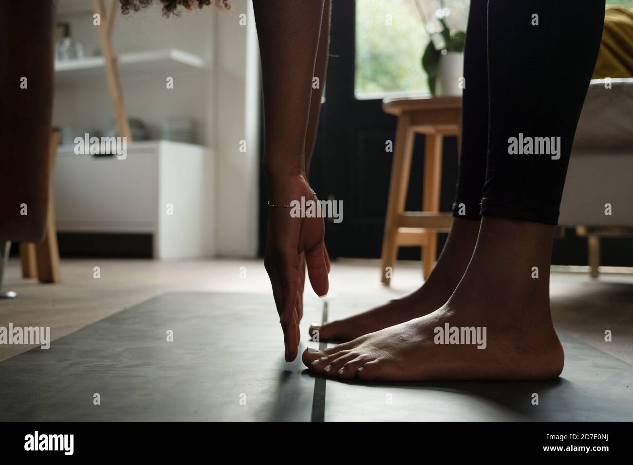 Une athlète féminine stretching des chaînes de hameaux pendant le flux de yoga dans le salon moderne Banque D'Images