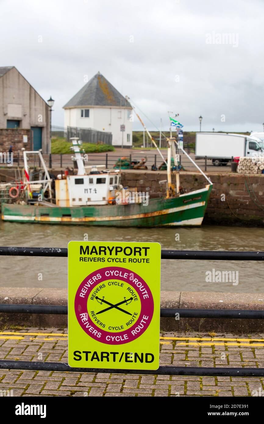 Un bateau de pêche dans le port de Maryport, Cumbria, Royaume-Uni avec une sdign pour la piste cyclable de la ville de Univers. Banque D'Images