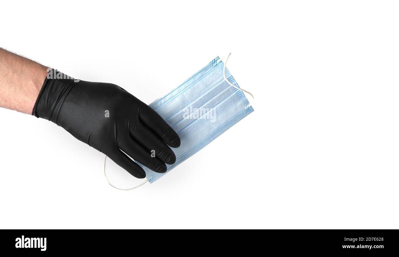 main dans le gant en latex noir tient un masque médical jetable sur fond blanc Banque D'Images