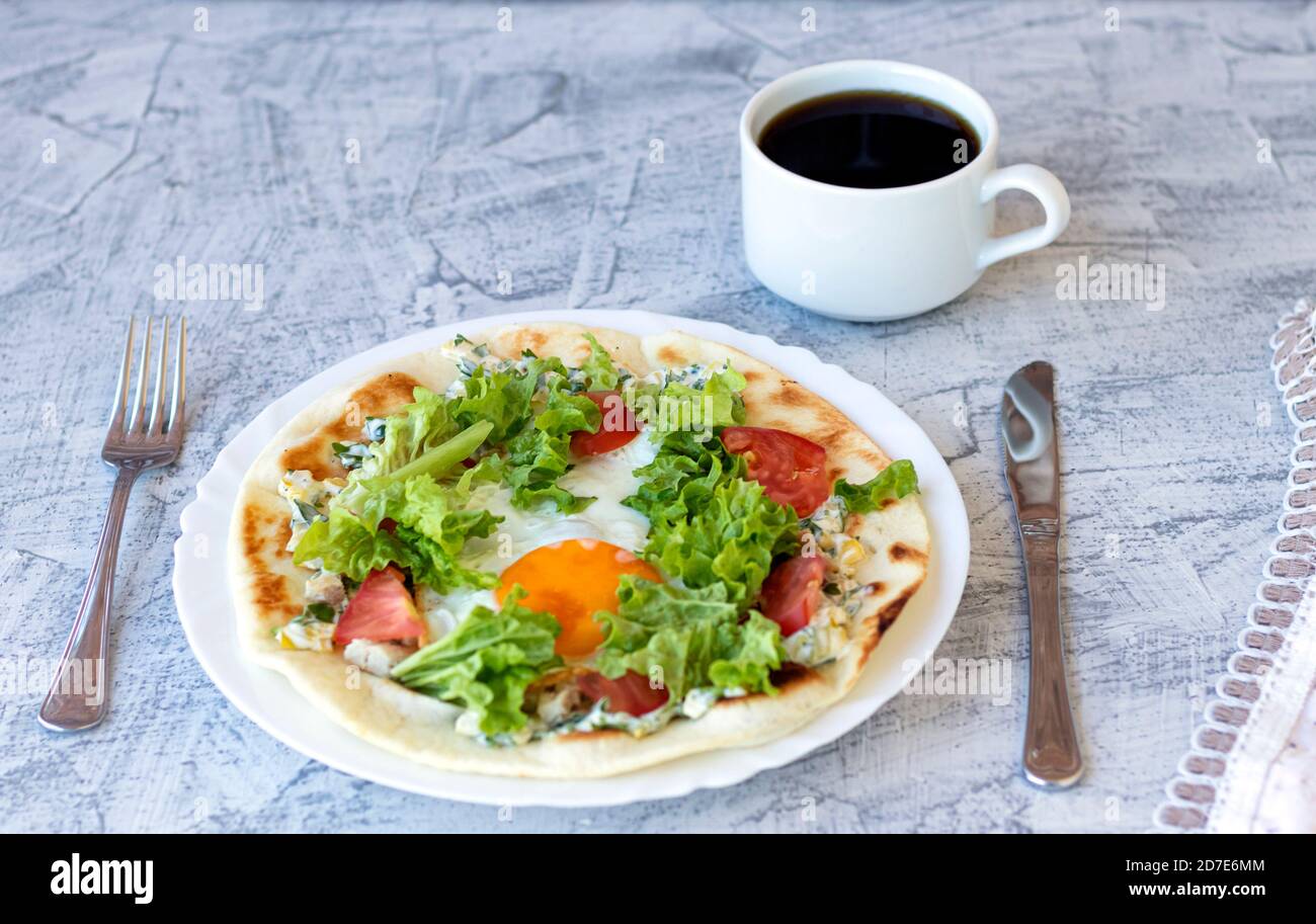 Petit-déjeuner italien avec café. Piadina avec œuf, tomates et salade. Délicieux petit déjeuner servi sur table avec serviette. Mise au point douce Banque D'Images