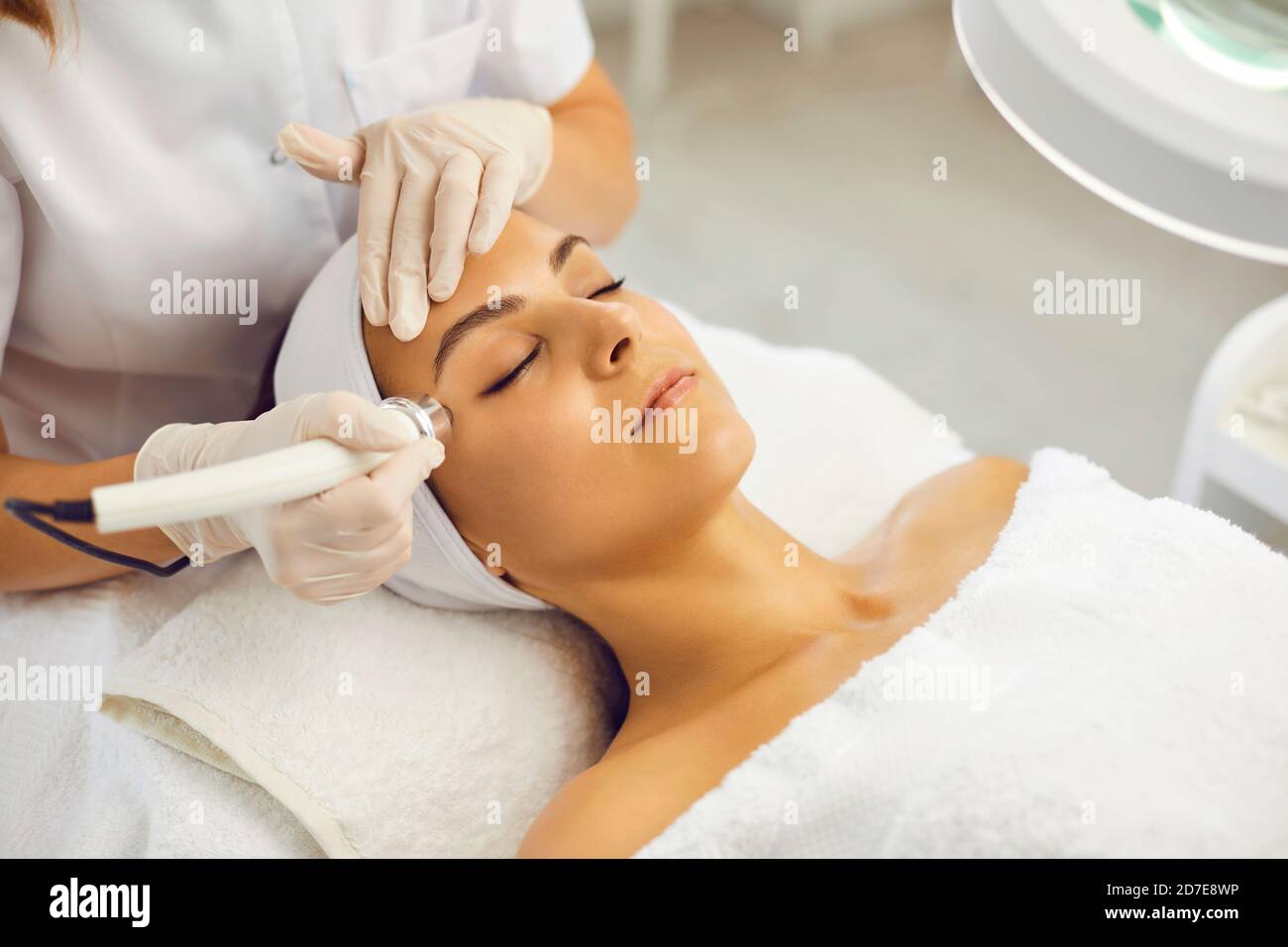 Cosmetologiste de faire l'aspirateur visage de nettoyage de peau pour la jeune femme dans salon de beauté Banque D'Images