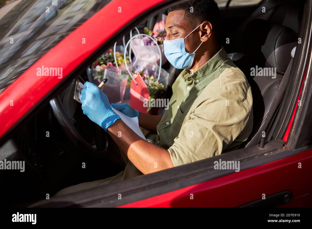 Artiste floral écrivant des informations dans une voiture avec une fenêtre ouverte Banque D'Images