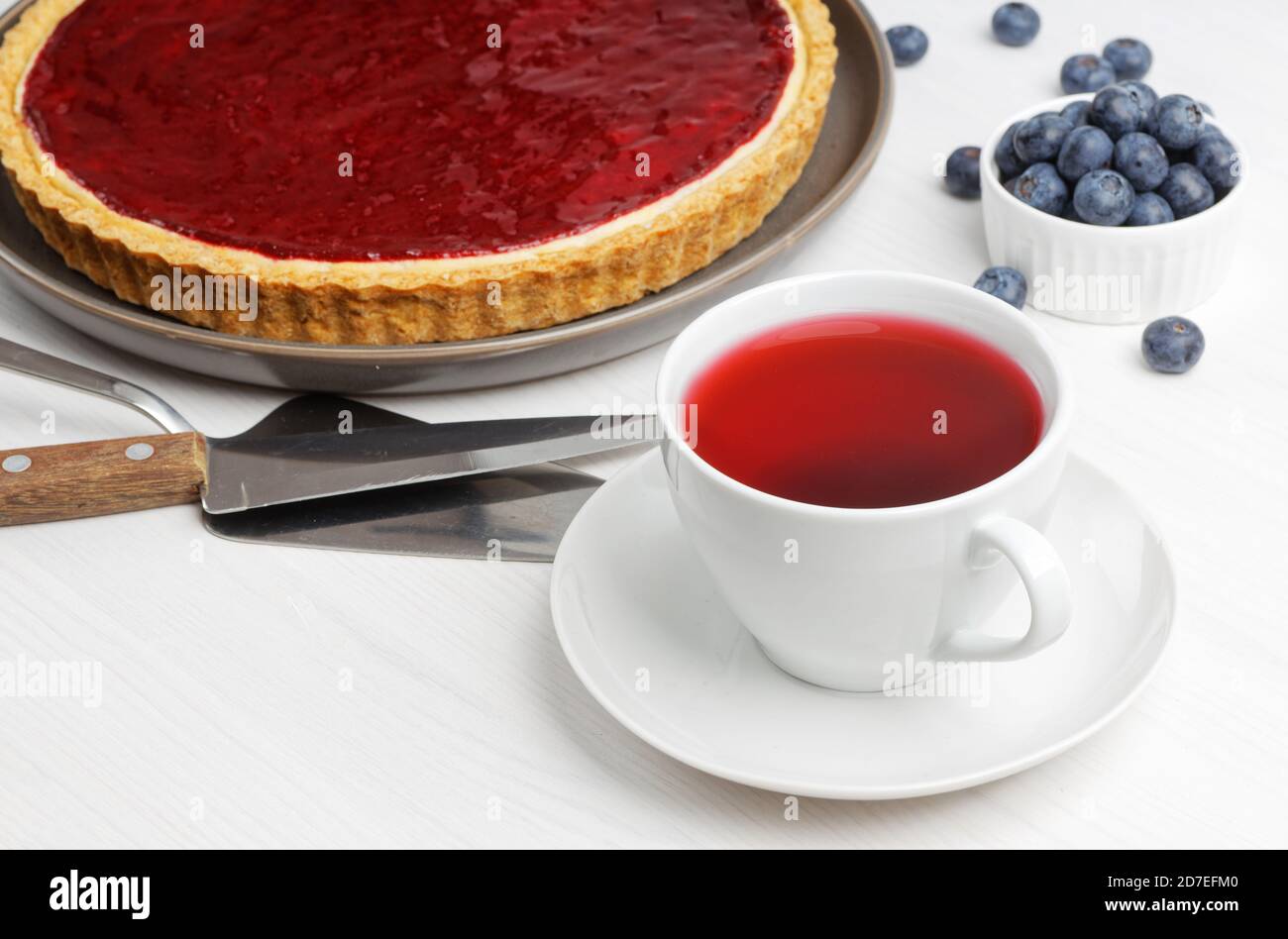 Tasse d'hibiscus de thé rouge et cheesecake maison avec gelée de baies sur table en bois blanc. Mise au point peu profonde. Banque D'Images