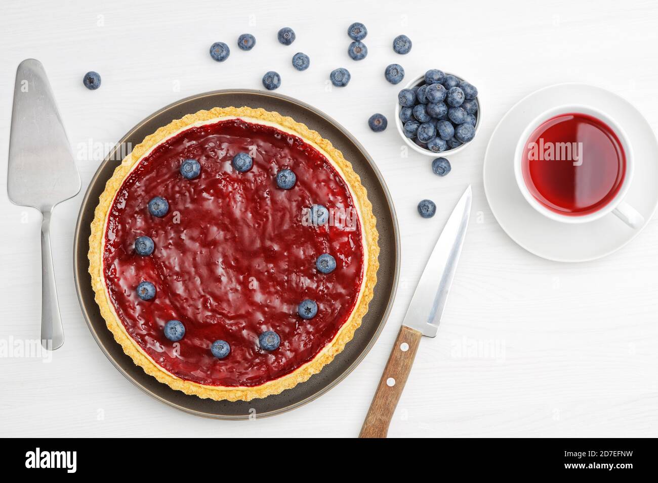 Cheesecake maison avec gelée de baies et une tasse d'hibiscus de thé rouge sur une table en bois blanc. Vue de dessus. Banque D'Images