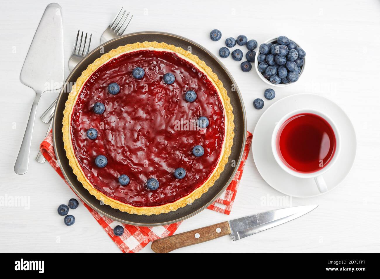 Cheesecake maison avec gelée de baies et une tasse d'hibiscus de thé rouge sur une table en bois blanc. Vue de dessus. Banque D'Images