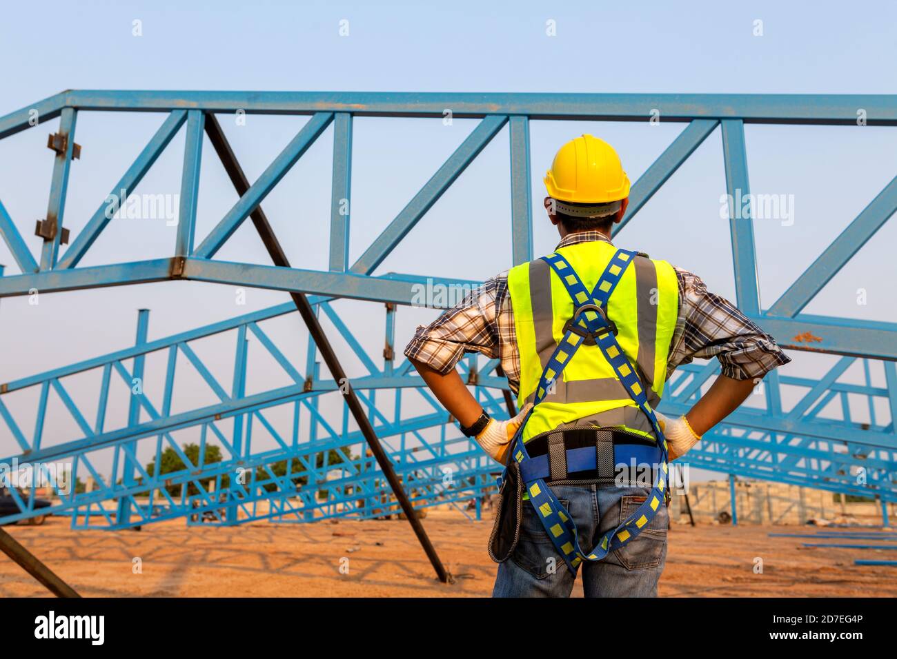L'arrière du travailleur de la construction portant un harnais de sécurité et une ligne de sécurité travaillant en hauteur sur le toit du chantier de construction. Banque D'Images