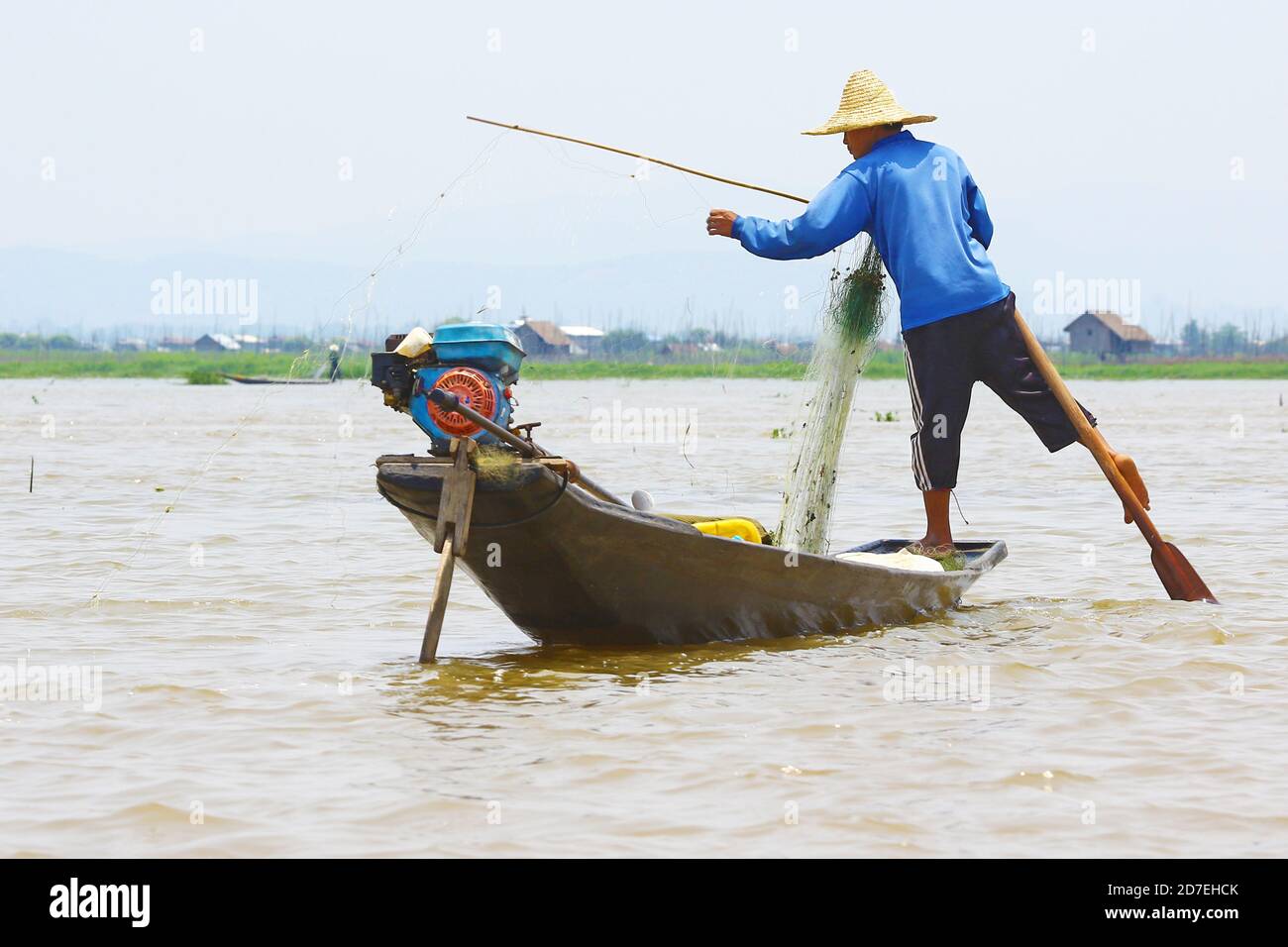 Pêcheur sur le lac Inle. Les habitants de la région pratiquent un style d'aviron distinctif, se tenant à la poupe sur une jambe et enroulant une jambe autour de l'aure. Banque D'Images