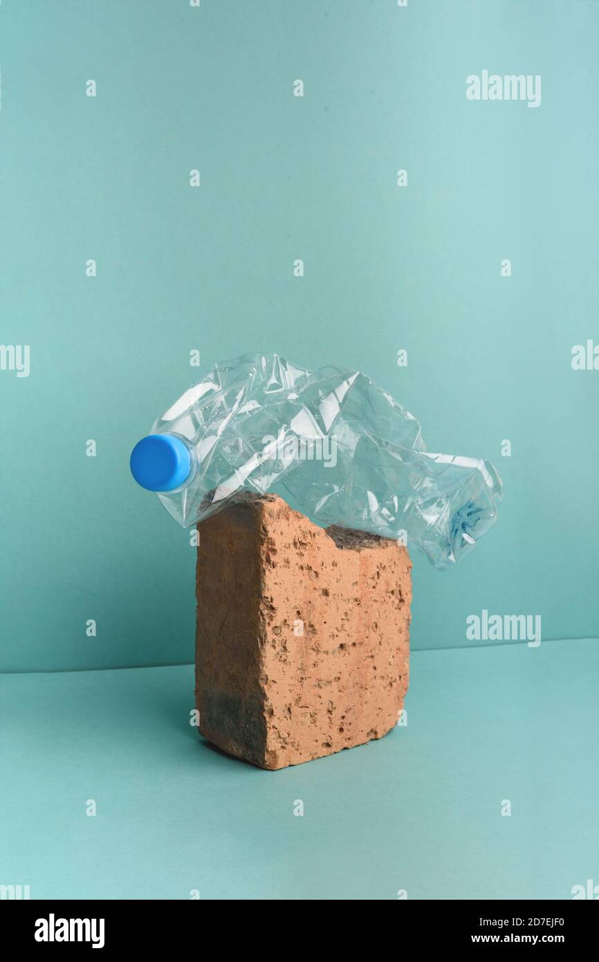 Utilisé bouteille en plastique écrasé sur pierre de brique sur fond bleu. Banque D'Images