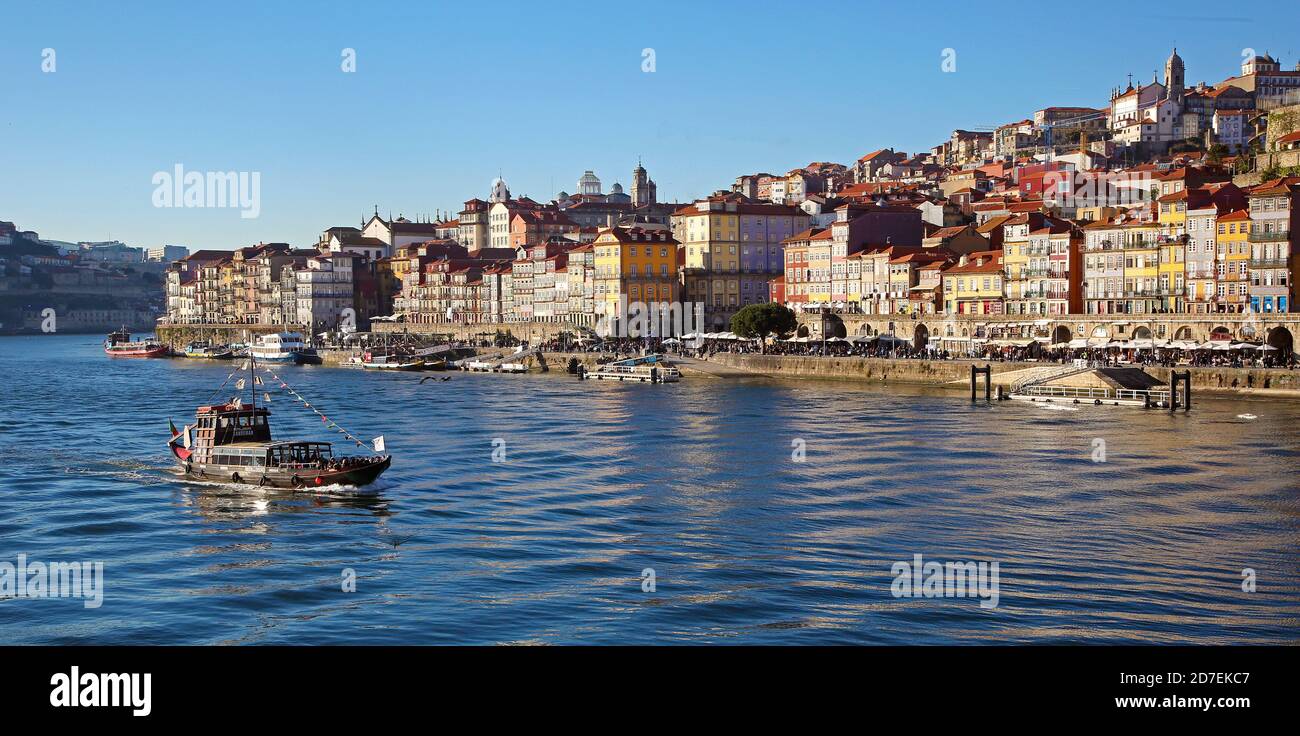 Porto et Douro. Le bord de la rivière droite du Douro. La vieille ville est en plein soleil tandis qu'un ferry touristique navigue en face de la ville. Banque D'Images