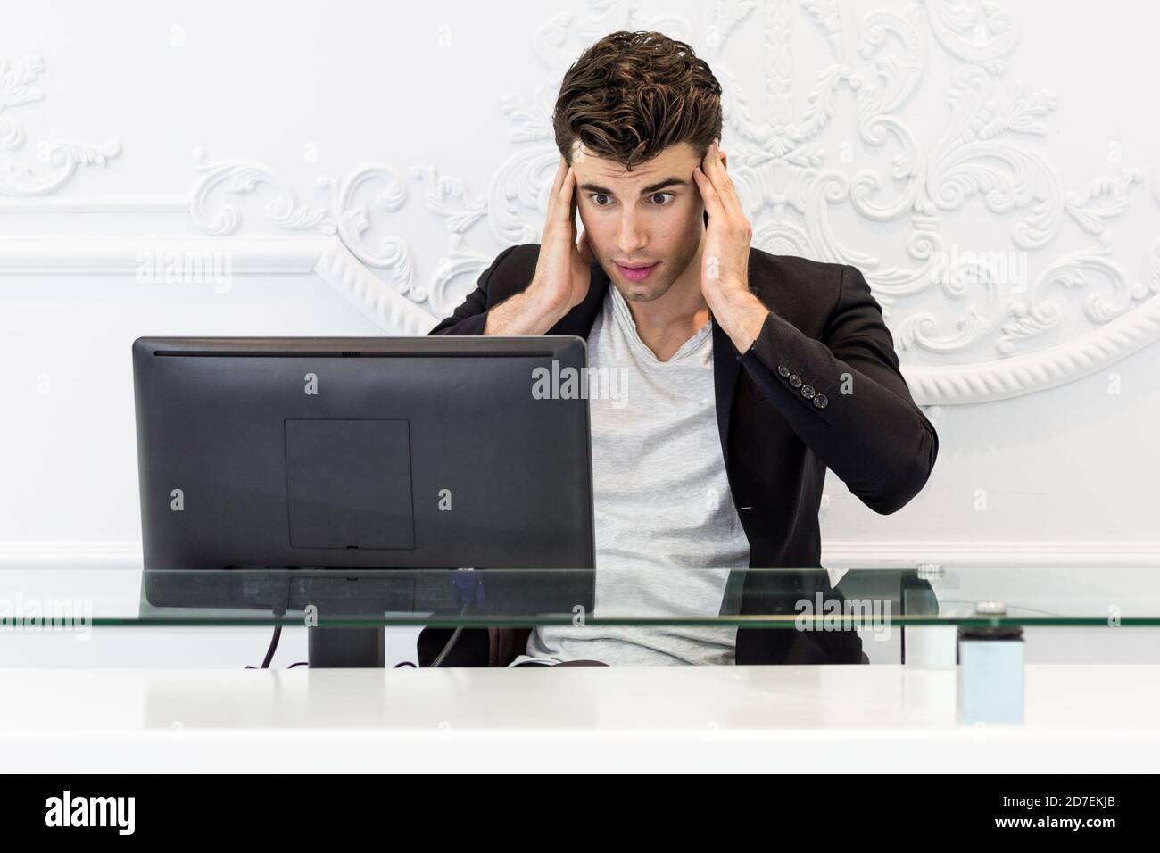 Homme d'affaires stressé et confus travaillant sur un ordinateur de bureau au bureau. Banque D'Images