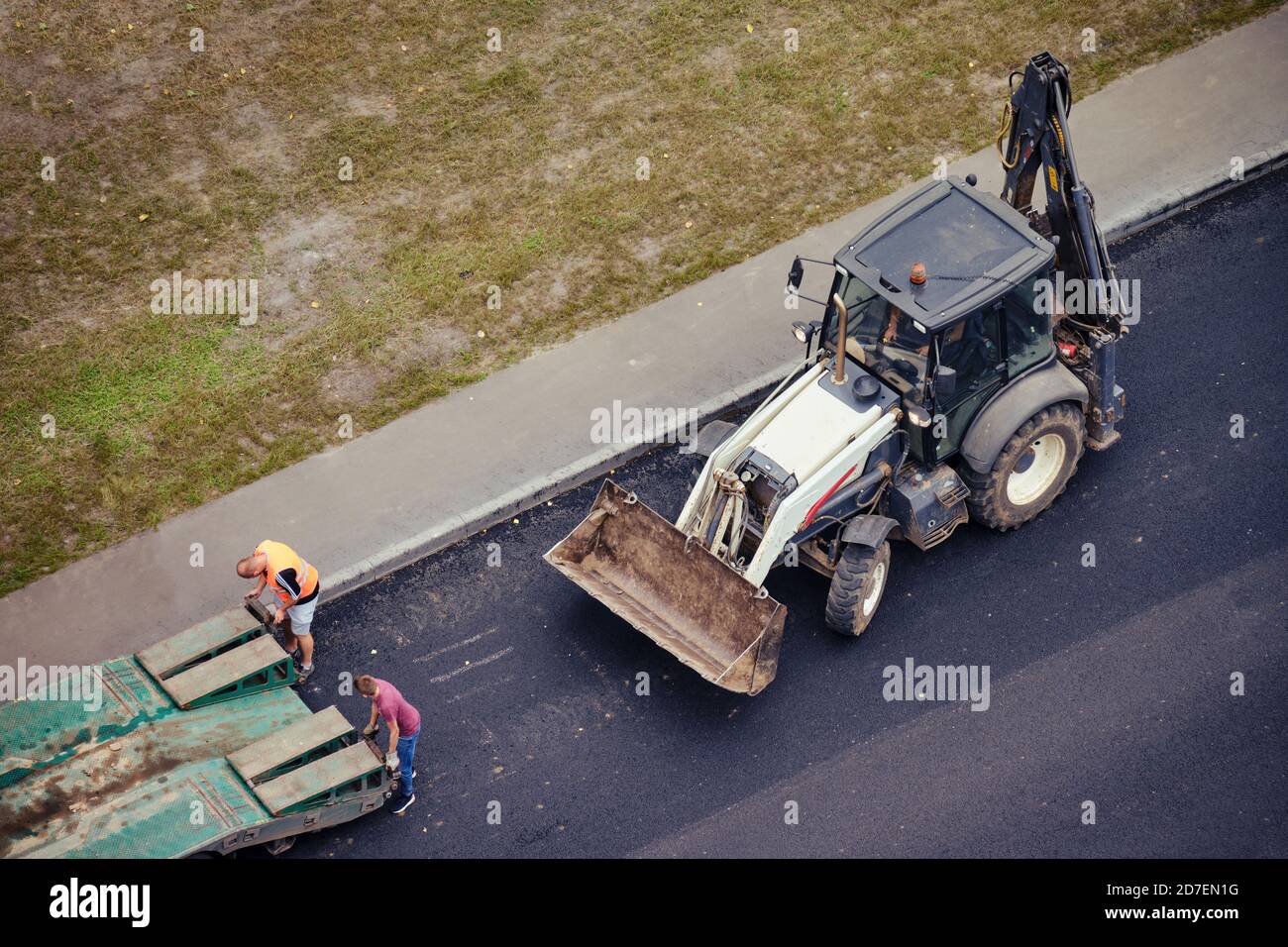 Les travailleurs chargent la pelle hydraulique de construction sur une remorque de camion pour le transport vers un autre emplacement Banque D'Images