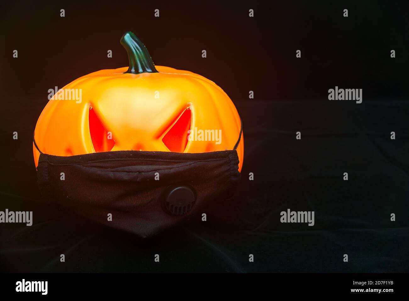 Citrouille d'Halloween méchante avec yeux rouges effrayants dans le masque facial. Fête d'Halloween 2020 avec pandémie de coronavirus. Polyuréthane orange décoratif isolé Banque D'Images