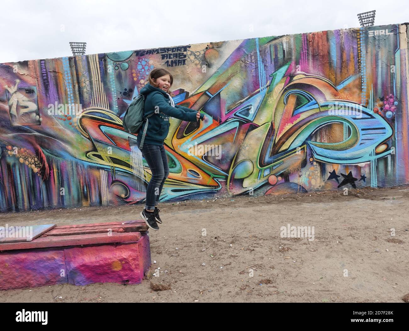 Fille qui saute devant le mur de Berlin Banque D'Images