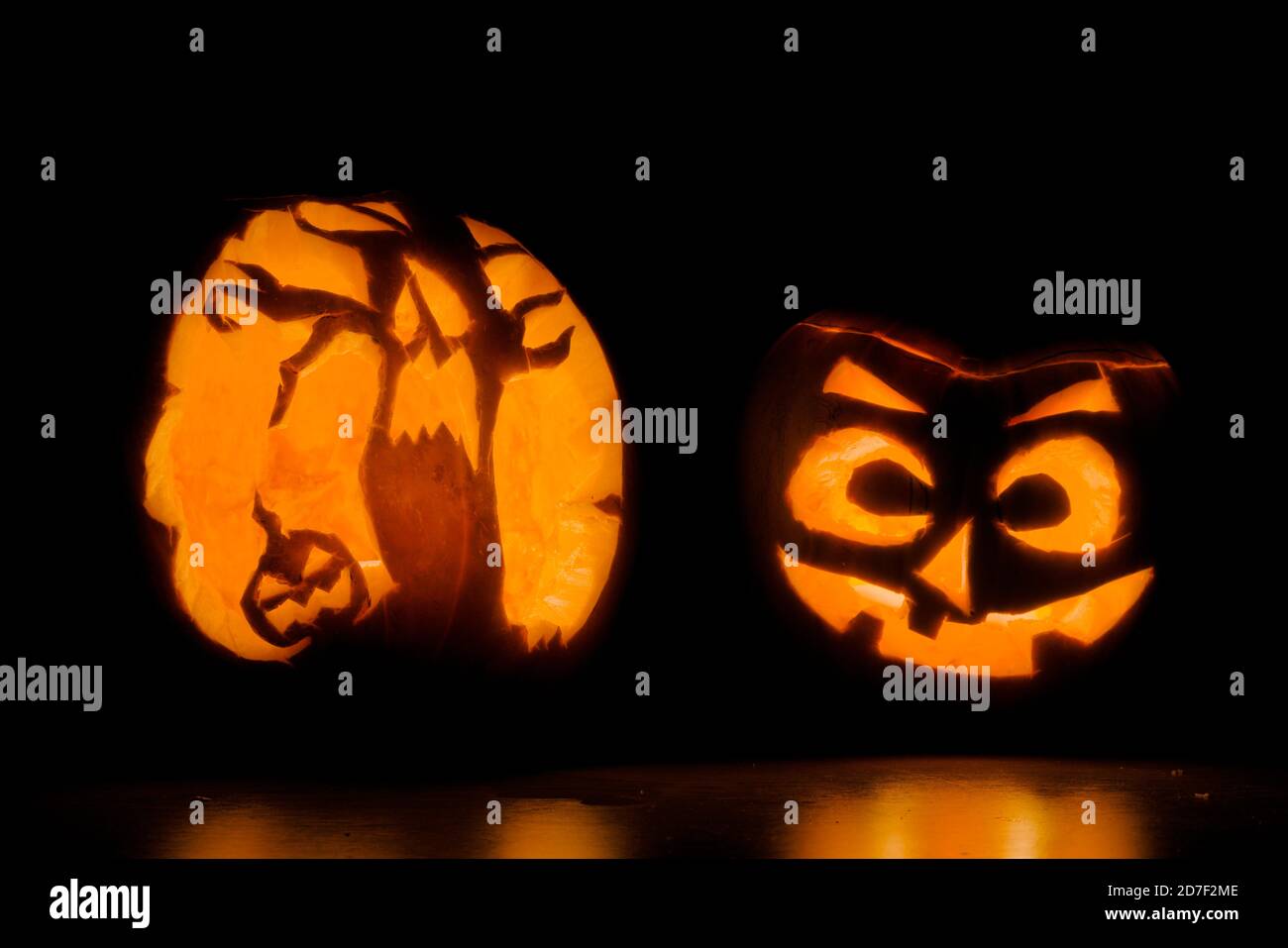 Deux citrouilles d'halloween finement sculptées éclairées par des bougies, l'une est d'un visage effrayant, et l'autre d'arbres terrifiants et une autre citrouille Banque D'Images