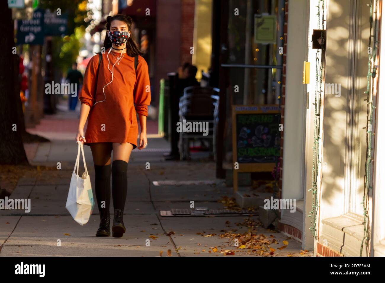 Frederick, MD, USA 10/14/2020: Une belle jeune femme portant un masque facial en raison de la pandémie de COVID-19 est en marche dans la rue dans le centre-ville de Frederick. Banque D'Images