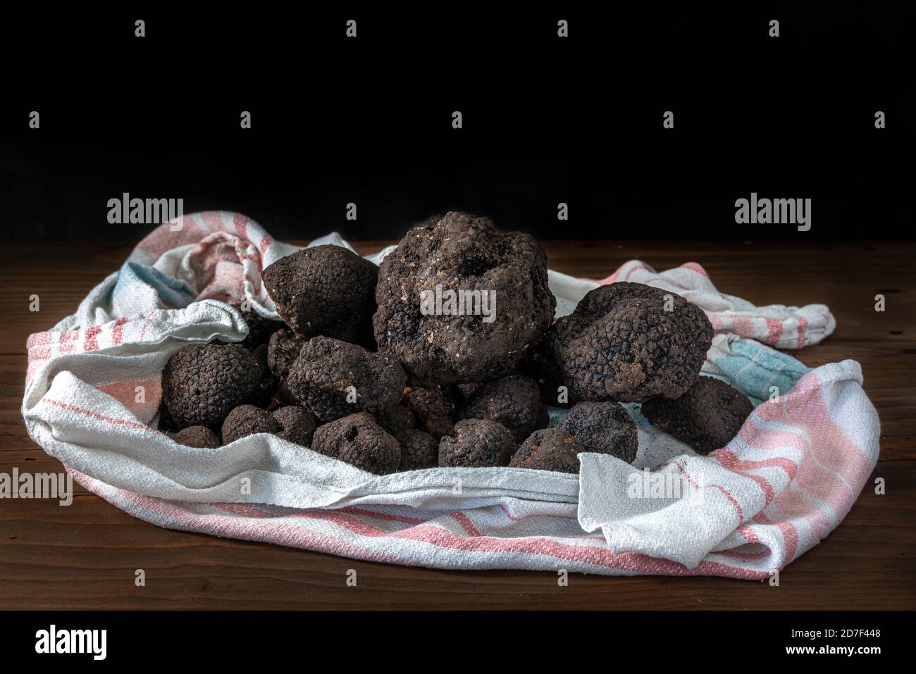 Truffes noires avec des traces de terre encore conservées dans un tissu placé sur une table sur un fond noir.Abruzzes, Italie, Europe Banque D'Images
