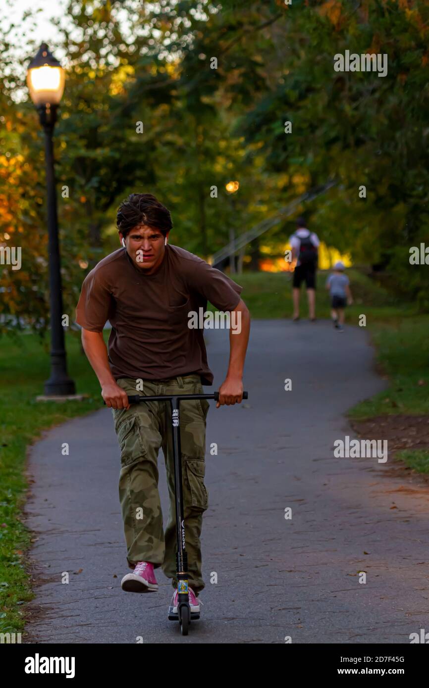 Frederick, MD, USA 10/14/2020: Un jeune homme hispanique portant des camo-caleçons et des sneakers transversales roses est à cheval sur un scooter à Baker Park. Il le pousse ha Banque D'Images