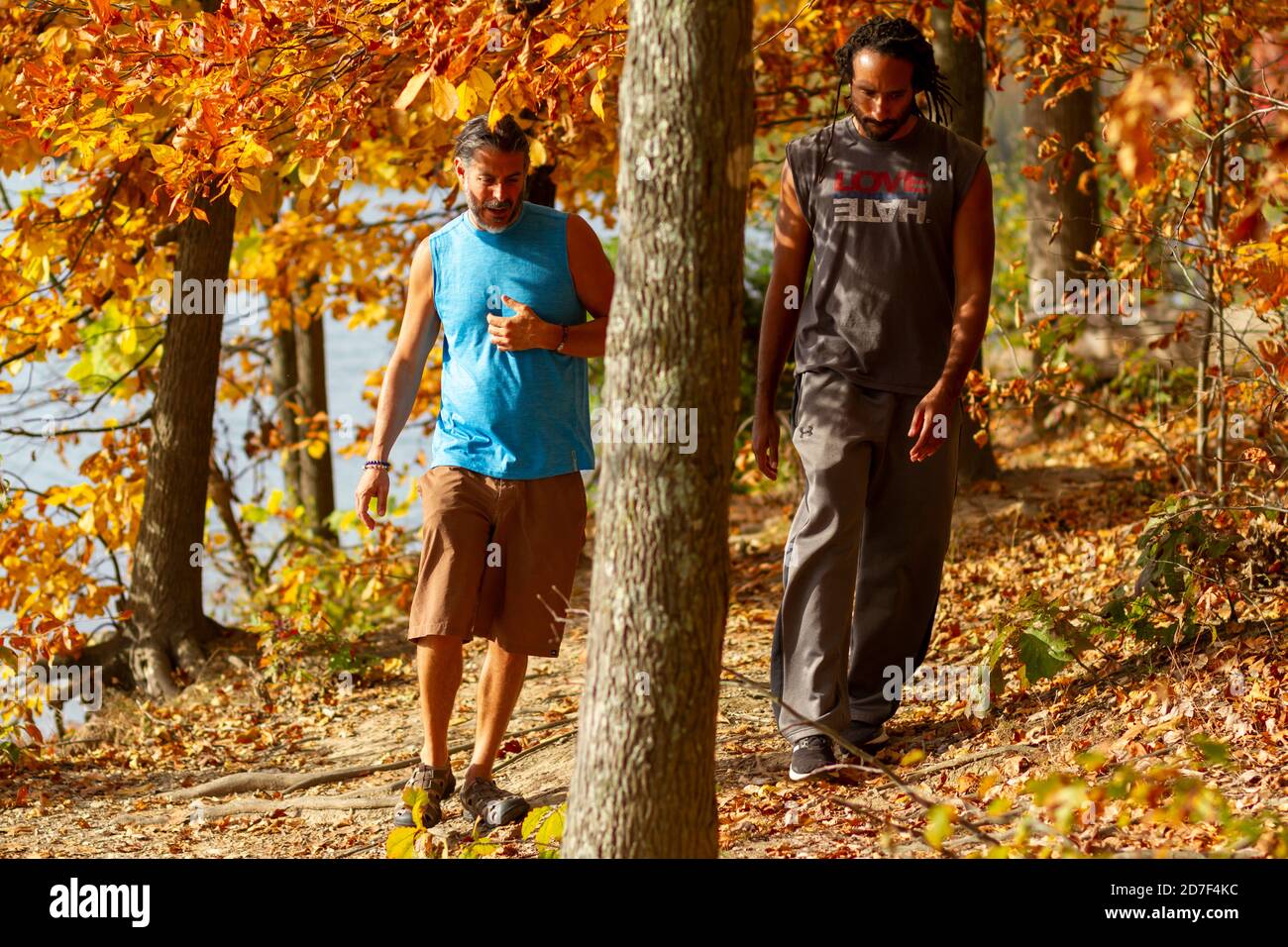 Boyd, MD, USA 10/20/2020: Un jeune homme athlétique afro-américain et son ami caucasien marchent ensemble sur un sentier de randonnée en forêt. La masse est en crique Banque D'Images