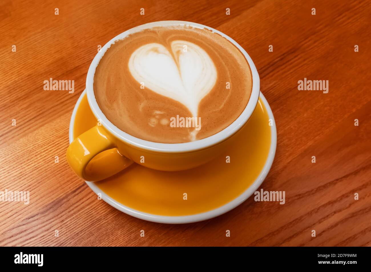 Tasse de café jaune avec latte en forme de coeur Banque D'Images