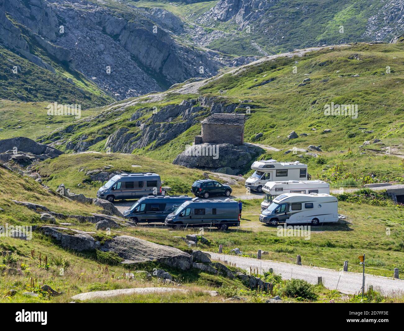 Mobile homes séjour nuit, parking sur la route historique Tremola, col de montagne Sasso San Gotthardo, ancienne église sur la colline, Suisse. Banque D'Images