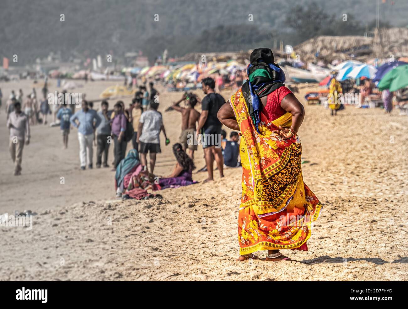 De belles femmes indiennes non identifiées dans des vêtements nationaux colorés se tient dessus plage dans une posture puissante et en regardant la plage pleine de touristes à pied Banque D'Images