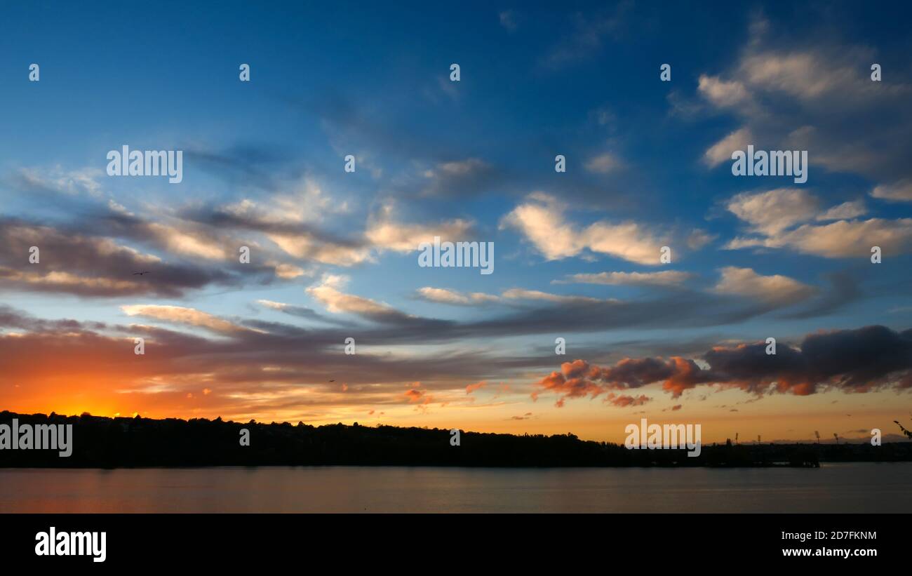 Un coucher de soleil incroyable sur l'eau. Magnifique paysage avec un lac et un ciel spectaculaire avec des cumulus nuages à l'horizon. Banque D'Images