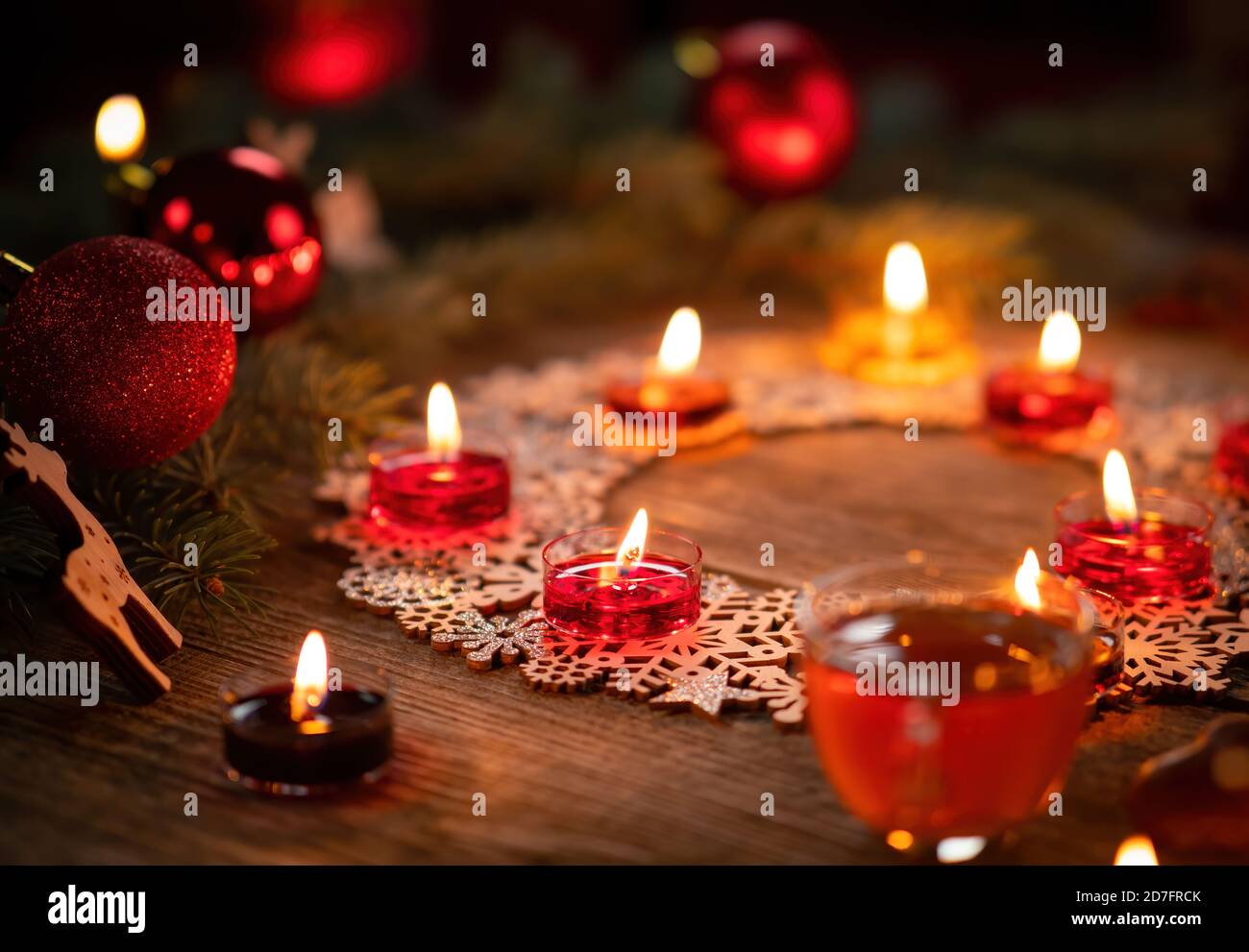 Décoration ornementale d'hiver avec bougies allumées sur table rustique en bois. Punch au vin chaud avec pain d'épice au premier plan. Vacances de Noël et nouveau Banque D'Images