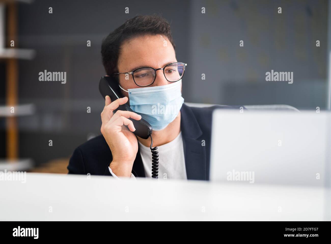 Réceptionniste homme à la réception du bureau portant un masque facial Banque D'Images