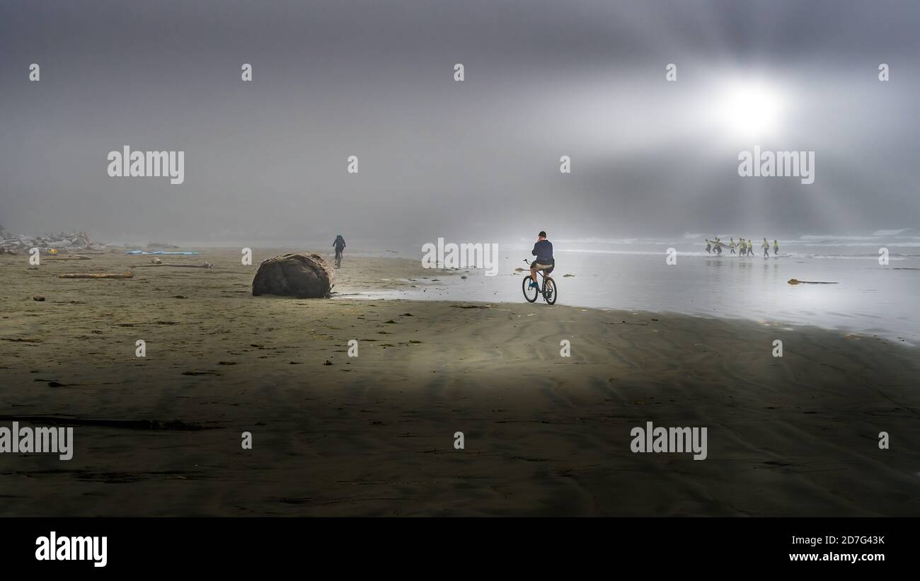Les cyclistes qui font du brouillard dense font du vélo sur la plage de Cox Bay, au parc national Pacific Rim, sur l'île de Vancouver, en Colombie-Britannique, au Canada Banque D'Images