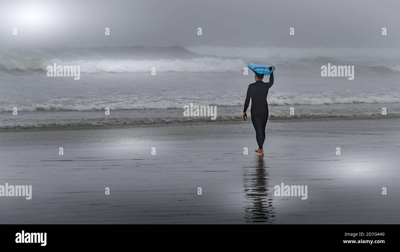 Surfez sur les vagues dans le brouillard dense pour surfer dans la baie Cox au parc national Pacific Rim sur l'île de Vancouver, Colombie-Britannique, Canada Banque D'Images