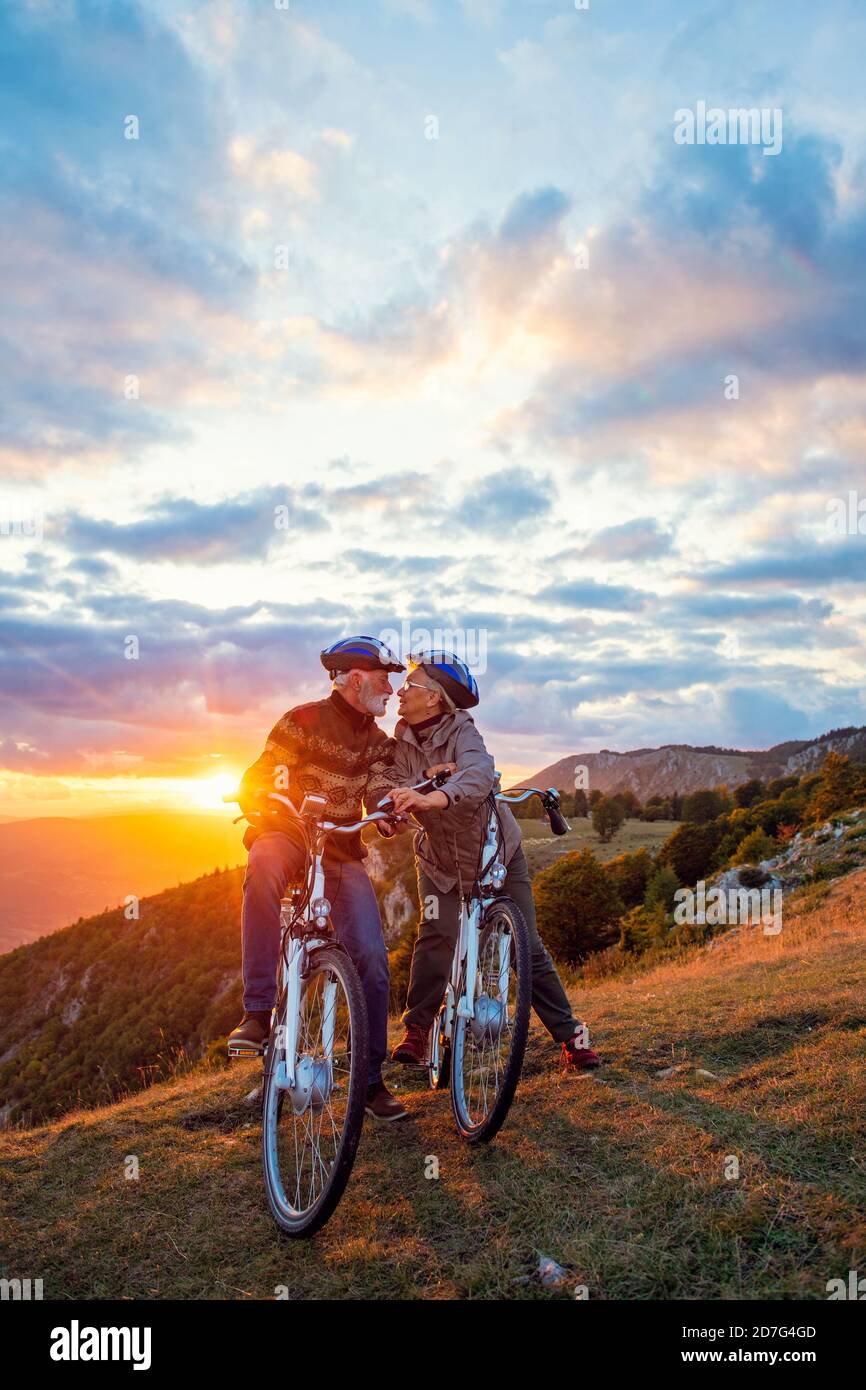 Couple senior actif sur une balade en vélo de campagne. Embrasser sur leur pause Banque D'Images