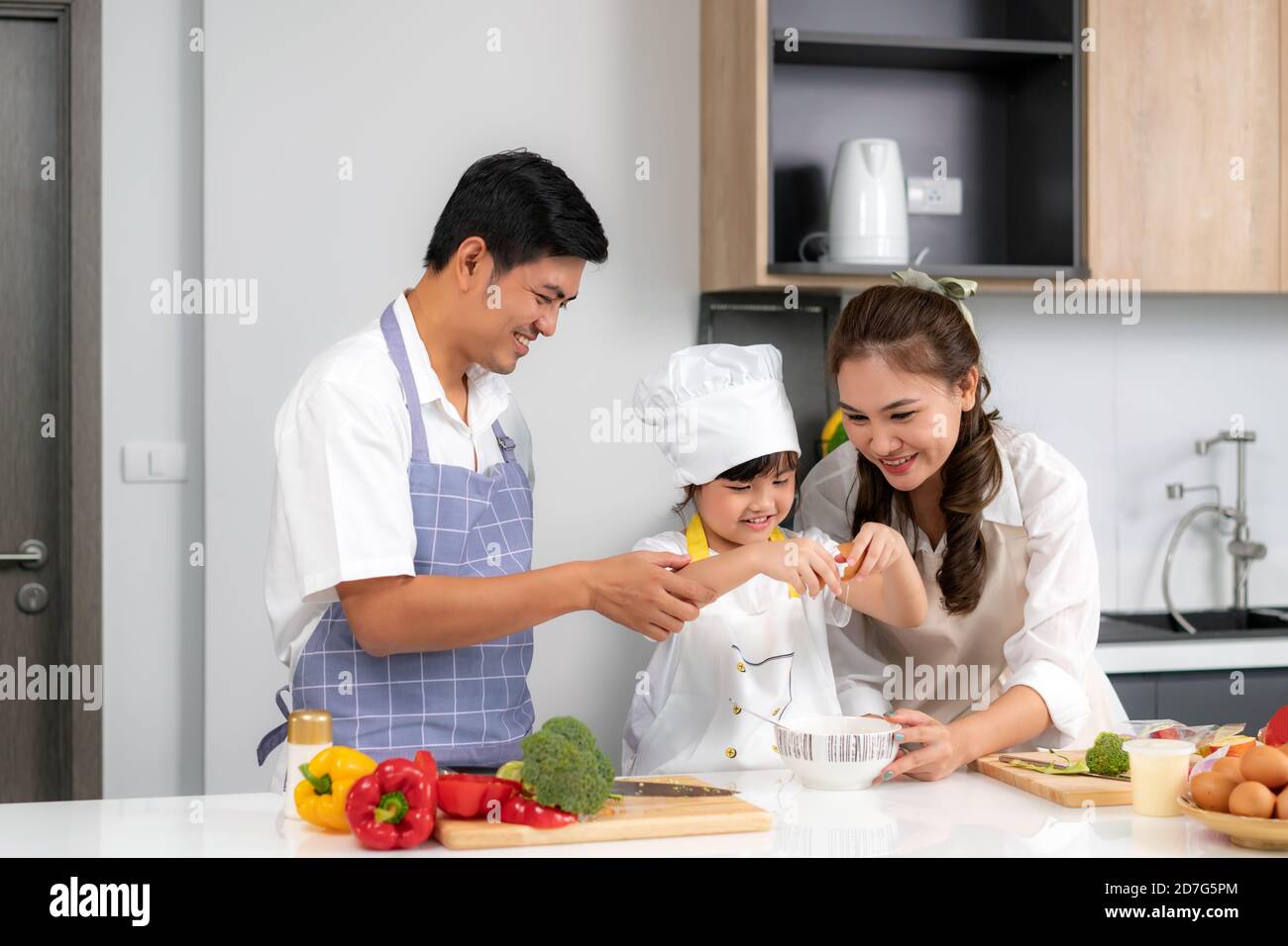 Les jeunes familles d'amour asiatiques préparent un dîner à table dans la cuisine à laquelle le père et la mère enseignant la fille cuisiner la journée à la maison Banque D'Images