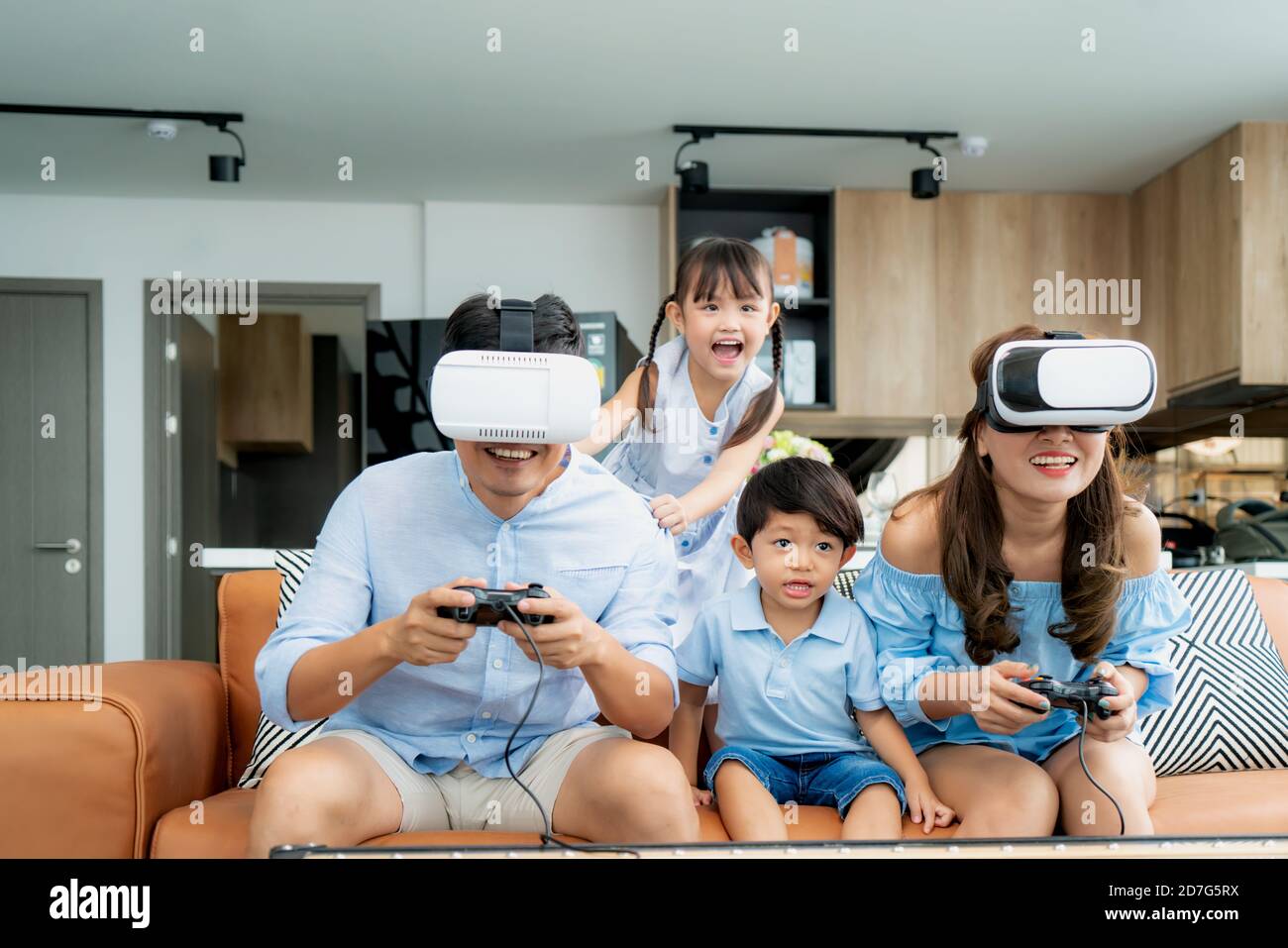 Bonne famille asiatique à la maison sur le salon canapé avoir s'amuser pendant qu'ils regardent la mère et le père jouant des jeux Utilisation du casque de réalité virtuelle VR dans l Banque D'Images