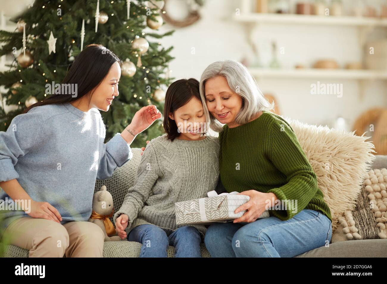 Bonne mère obtenir cadeau de Noël de ses deux filles elles Fêtez Noël à la maison Banque D'Images