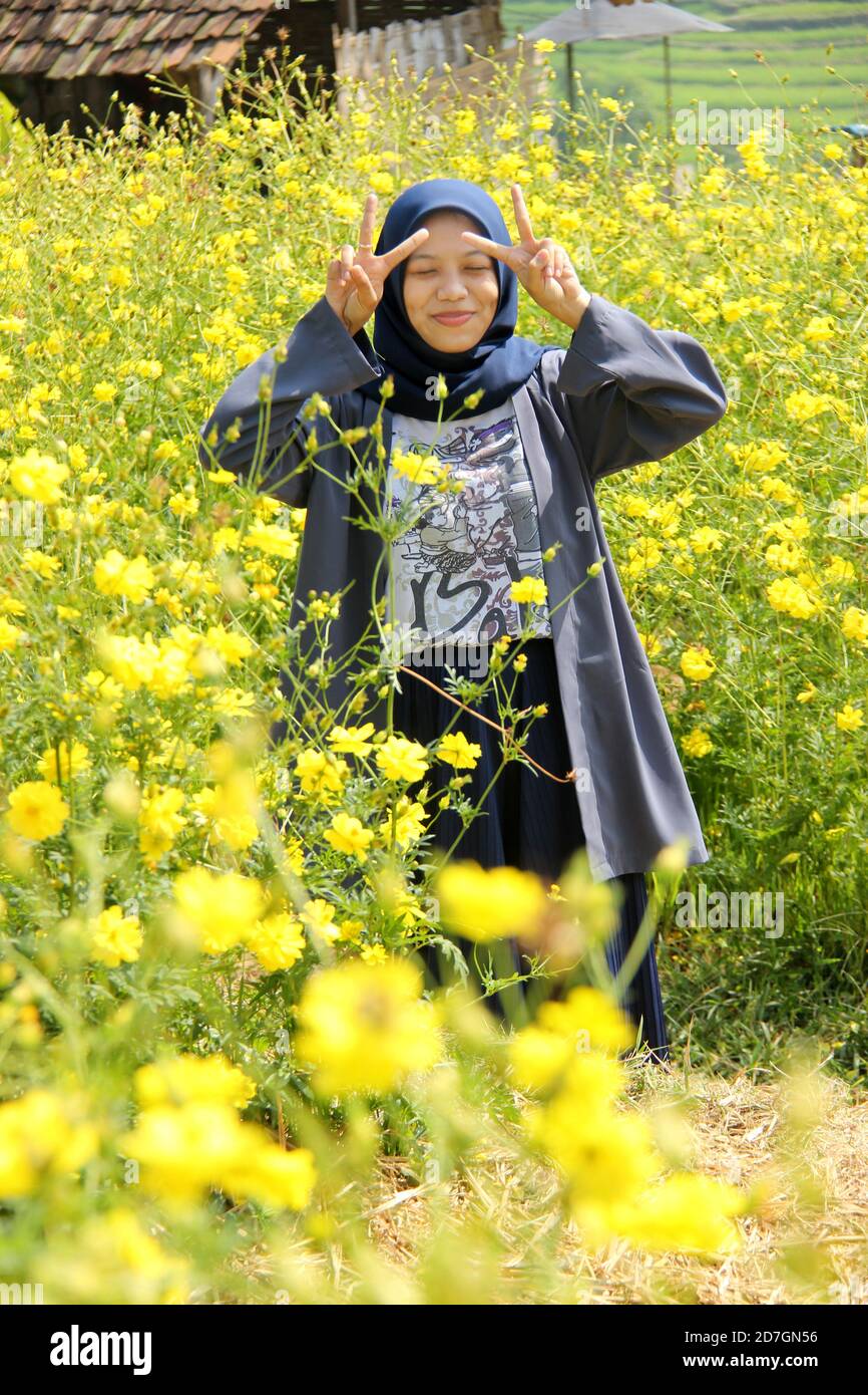 portrait d'une femme asiatique posant dans un jardin de fleurs à rayons jaunes. Profitez d'une escapade d'un week-end sur le tourisme de nature Banque D'Images