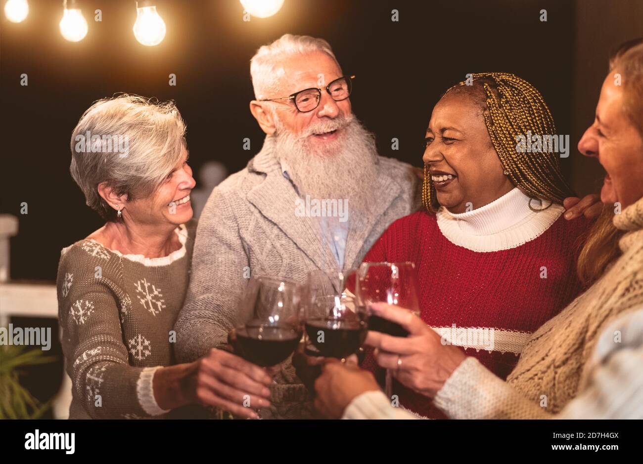 Des amis aînés heureux célèbrent les vacances tout en dégustant du vin rouge verres sur la maison patio fête Banque D'Images
