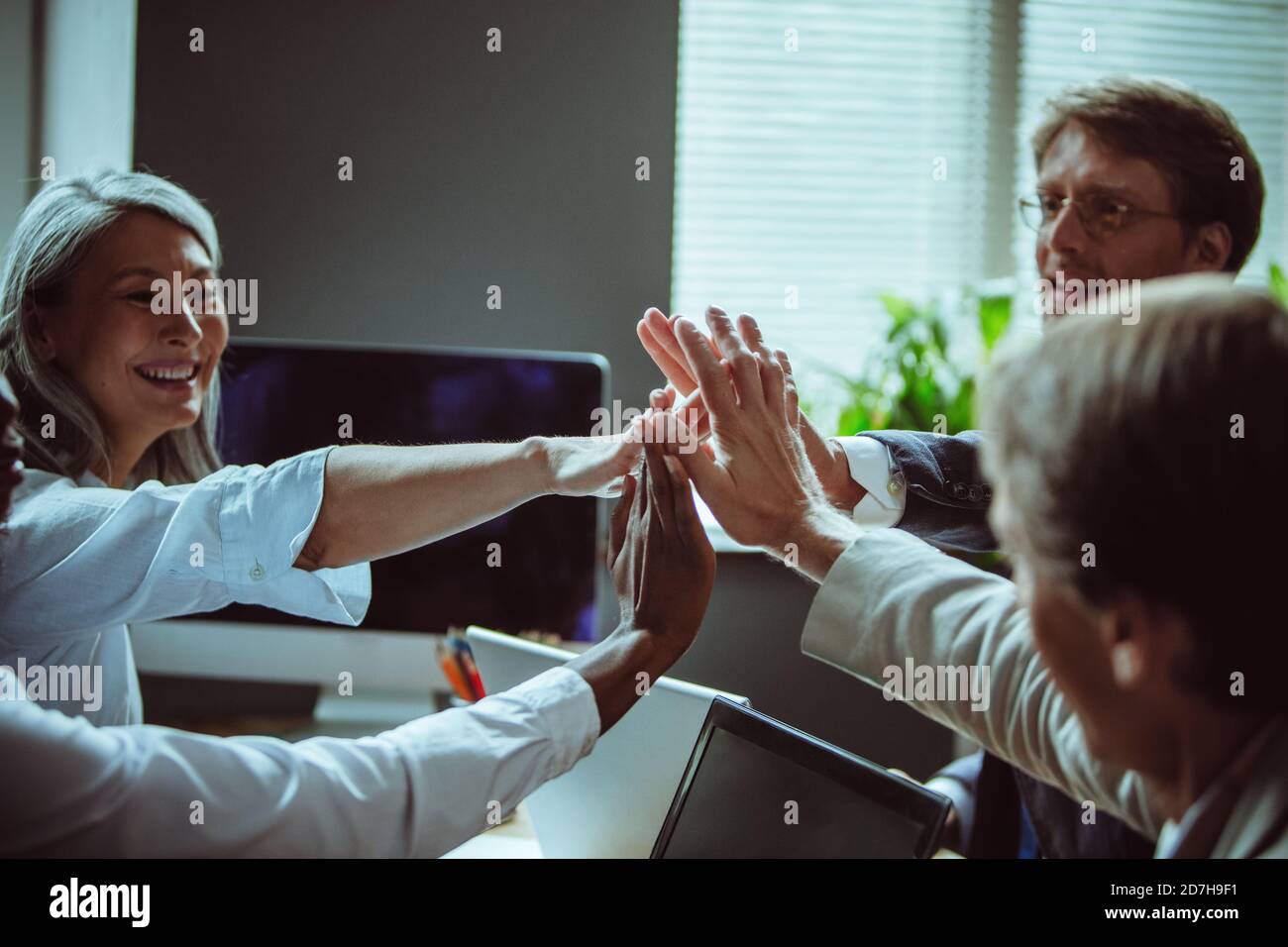 Une équipe heureuse d'hommes d'affaires qui se donnent cinq personnes au bureau. Accent sélectif sur les mains humaines connectées au centre. Brainstorming Banque D'Images