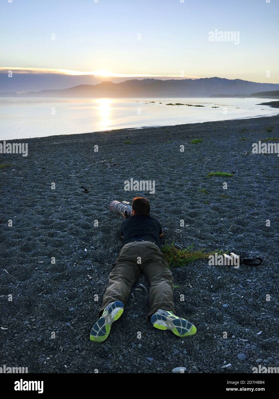 Photographe d'oiseaux couché sur la plage, essayant de photographier le wader avec contre-jour, Nouvelle-Zélande, île du Sud, Kaikoura Banque D'Images