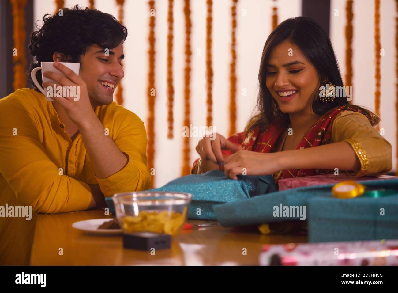 Un jeune couple passe du temps tout en emballant des cadeaux Diwali Banque D'Images