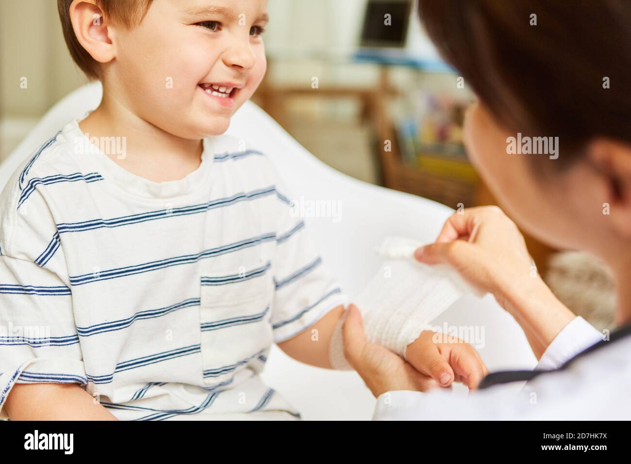 Le pédiatre attache un bandage de gaze autour du poignet blessé de l'enfant après un accident Banque D'Images Le pédiatre attache un bandage de gaze autour du poignet blessé de l'enfant après un accident Banque D'Images