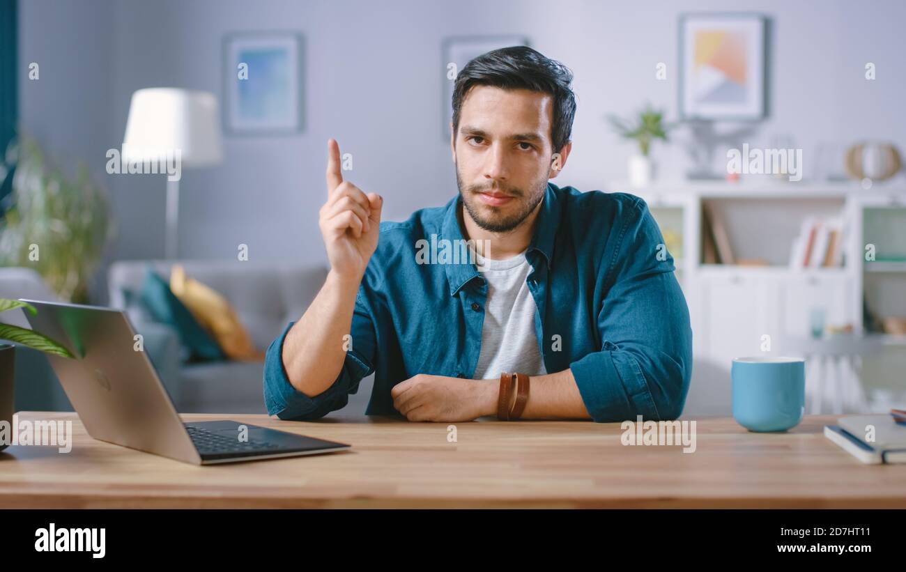 Un homme sérieux assis à son bureau à la maison lève son doigt et le agette, avertissement de ne pas faire quelque chose de mauvais. Honte sur vous geste. Banque D'Images